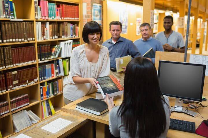 Maedchen bekommt beim Schreibtisch ein Buch überreicht