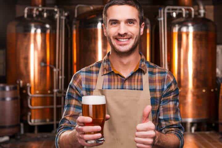 junger Brauer mit einem Bier in der Hand