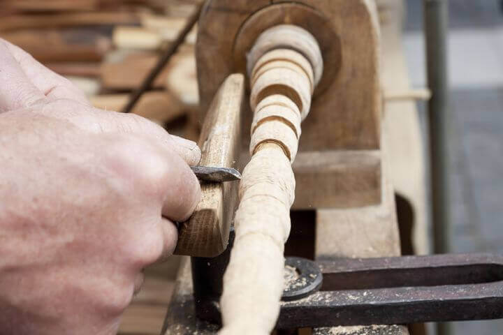 Haende die Holz auf einer Drechselbank bearbeiten