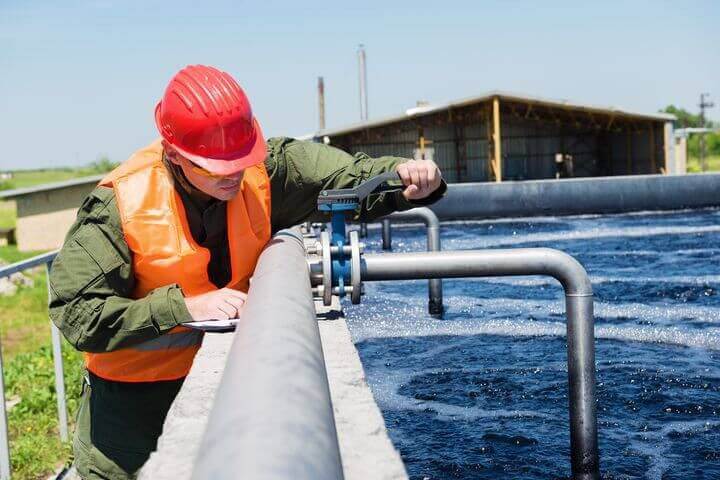 Mann schraubt die Wasserleitung in den Tank fest