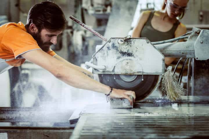 Steinmetz haelt Stein beim schneiden