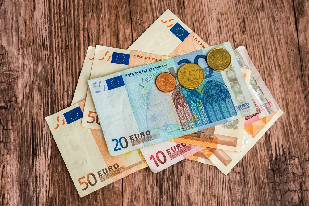 Lehrlingsportal.at Euro-Banknoten und -Münzen liegen auf einer Holzoberfläche ausgebreitet.