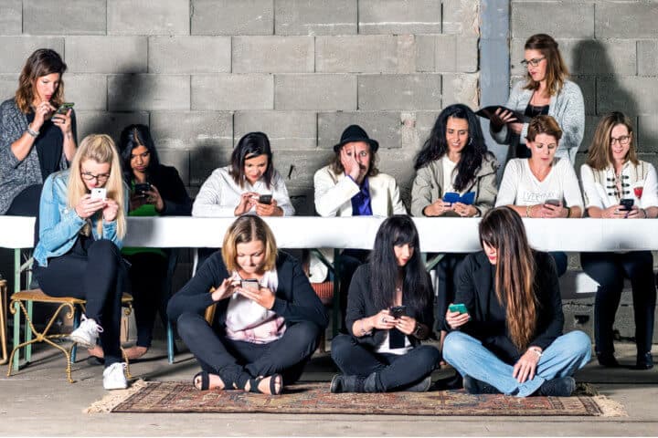 Lehrlingsportal.at Eine Gruppe von zwölf Personen, elf Frauen und ein Mann, sitzt in einem Raum mit einer Betonblockwand und telefoniert.