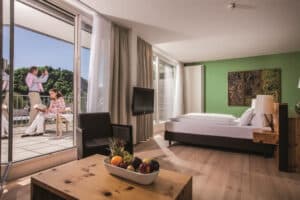 Hotelzimmer mit Doppelbett und Gästen am Balkon