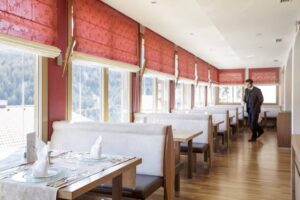 gedeckte Tische im Hotelrestaurant mit Blick auf verschneite Berge