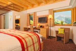 Hotelzimmer mit Doppelbett und TV mit Ausblick auf Berge