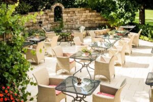 Cafe im Garten mit hellen Stühlen und Glastischen im Sommer