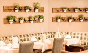 gedeckte Tische in Hotelrestaurant und Blumendeko an Wand