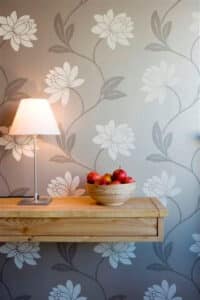 Blumentapete mit Sideboard, Tischlampe und Schale mit Äpfeln