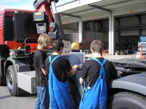 Lehrlinge mit Ausbildner am Laptop beim Kran