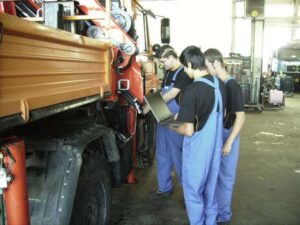 Lehrlinge mit Laptop bei LKW