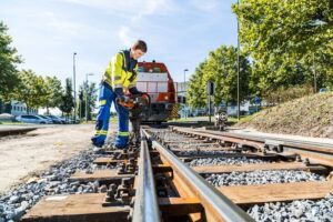 Lehrling in Arbeitskleidung arbeitet an Bahngleisen