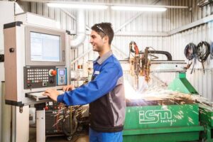 Lehrling mit Arbeitskleidung arbeitet an einer cnc-Maschine