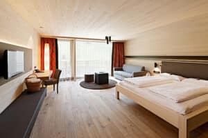 geräumiges Hotelzimmer in Holz verkleidet mit Doppelbett und TV